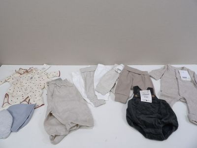 many baby clothes laid out on a white table