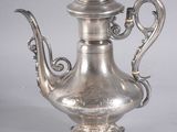 pair of antique silver teapots on pedestal on grey background