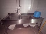 un lavabo en acier inoxydable dans une salle de bains avec une poubelle bleue