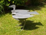 a metal bird that is sitting in the grass
