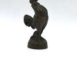 bronze figurine of a rooster on a rock on a white background