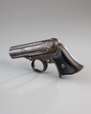 un vieux pistolet en forme de pistolet posé sur une surface blanche