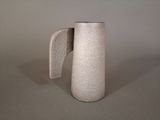 a white pitcher with a handle sitting on a table