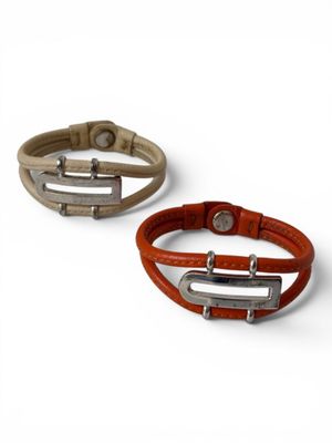 two leather bracelets with metal clasps on a white background