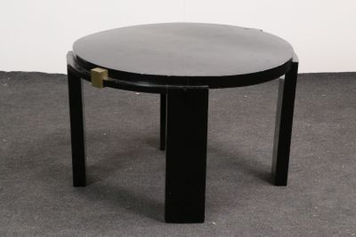 une table noire avec un plateau rond en verre, posée sur un sol recouvert de moquette