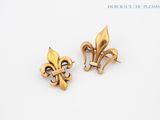 deux boucles d'oreilles en forme de fleur de lys dorées sur fond blanc