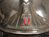 a shiny metal object with a red crest on it