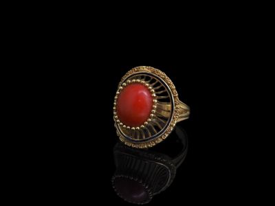 une bague en or sertie d'une pierre rouge sur un fond noir