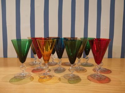 six verres à vin posés sur une table, avec un mur rayé en arrière-plan