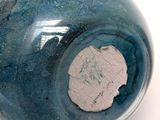 a blue vase with a hole in it on a white surface