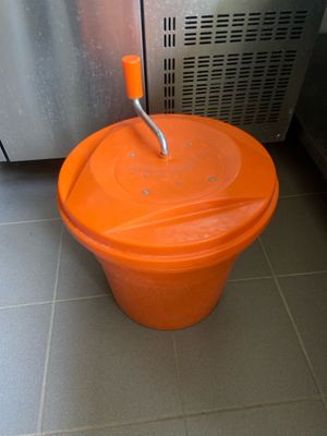 un seau orange posé par terre devant un réfrigérateur