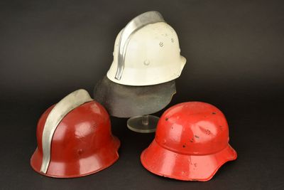 trois casques rouges et blancs posés les uns à côté des autres sur une surface noire