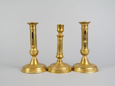 trois chandeliers en or posés les uns à côté des autres sur une table