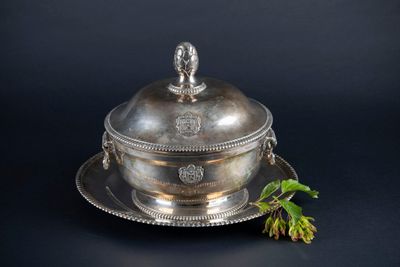an antique silver plate with a lid and a flower on a black background