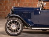 an old blue car parked in front of a brick wall