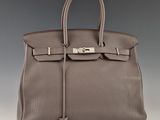 un sac à main en cuir gris muni d'un fermoir métallique sur la poignée