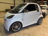 a small white smart car parked in a garage