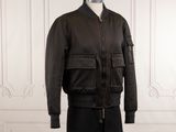 La veste est noire et comporte une fermeture éclair sur le devant.