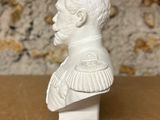 white ceramic bust of a man with a ruffled collar on a wooden table