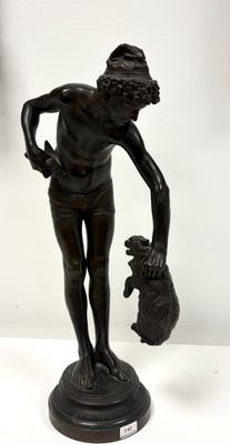 statue en bronze représentant un garçon avec un chien, posée sur un socle