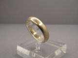 une bague en or posée sur un socle transparent