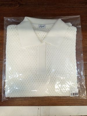 La chemise est blanche et est parsemée de pois.