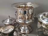 silver plated dishes and silverware on a table with a gray background