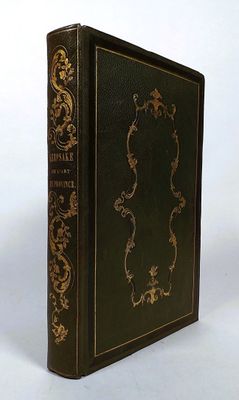 an old black book with gold trim sitting on top of a white surface