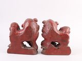 two red rooster figurines sitting on a white surface