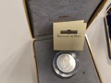 a silver coin sitting in a box next to a lighter