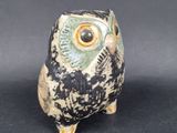 a small owl figurine sitting on a black surface