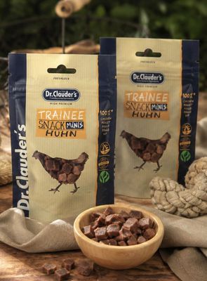 deux sachets de friandises pour chien posés sur une table, à côté d'un bol de nourriture