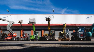 de nombreux engins de chantier de différents types garés devant un immeuble