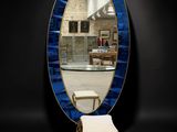 an oval mirror with a blue frame and a bench in front of it