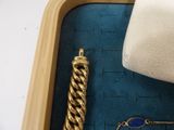 a white purse and a gold bracelet in a box