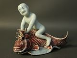 a figurine of a boy riding a fish
