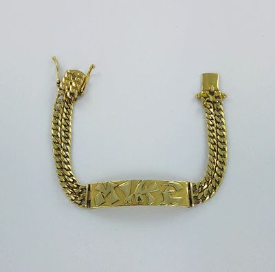 un bracelet en or muni d'un fermoir à barre et d'une chaîne