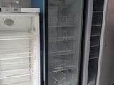 two empty refrigerators in a kitchen with a red bucket on the floor