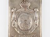 une vieille plaque en argent sur laquelle figurent une couronne et des armoiries