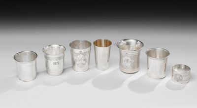 un ensemble de tasses et de cuillères en argent posées sur une surface blanche