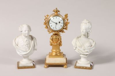 trois statues et une horloge exposées sur une table