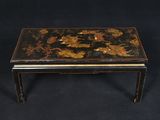 une table basse noire et dorée sur laquelle sont disposées des fleurs
