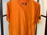 un t-shirt orange suspendu à un portant dans une pièce