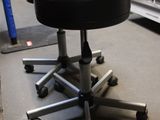 a black stool sitting on top of a metal stand