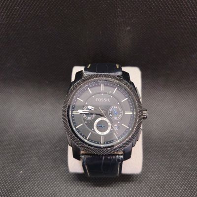 La montre est noire et possède un cadran argenté.