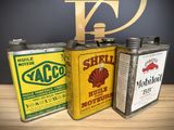 three old oil cans are sitting on a table next to each other
