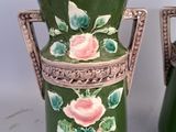 pair of green vases with pink roses on them sitting on a table