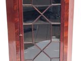 a small wooden cabinet with a glass door on it