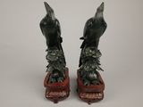 pair of bronze birds on a wooden stand with a white background