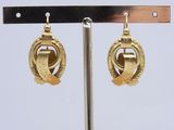 paire de boucles d'oreilles dorées, ornées d'un motif circulaire monté sur une tige métallique